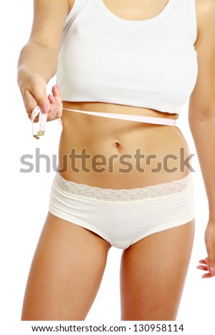 A female is measuring her waist whith measure tape - close-up on white background