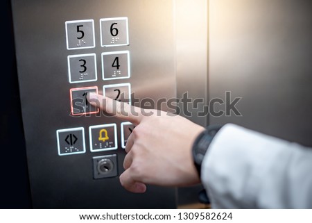 Male forefinger (index finger) pressing on the first floor button or floor number one in elevator (lift). Mechanical engineering concept