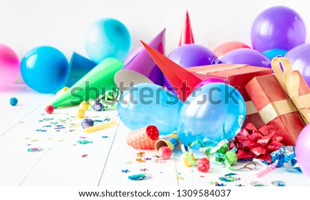Birthday party background with decoration, balloon, confetti, serpentine, birthday hat and gift boxes on white wooden teble