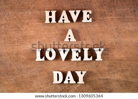 Have a lovely day word in wooden block letters on old wooden board.