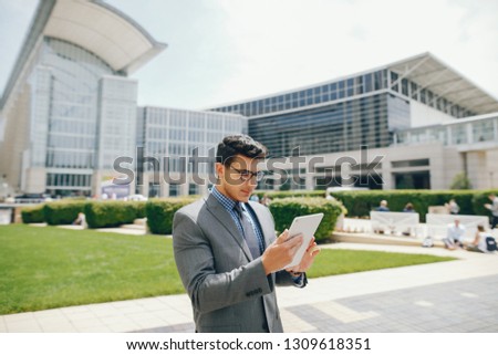 Handsome businessman in a city. Businessman in a glasses. Man with white tablet standing in a city