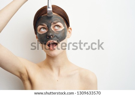 woman with open mouth apply clay mask on face with brush
