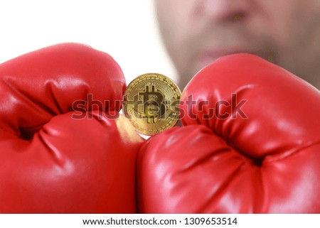 Man wearing red boxing gloves holding bitcoin symbol. Internet cryptocurrency state concept.