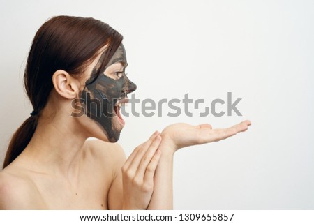 joyful woman in a clay mask holds a free place on her hand