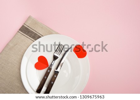 Festive table setting for Valentine's Day with fork, knife,  hearts on a red background. Top view. - Image