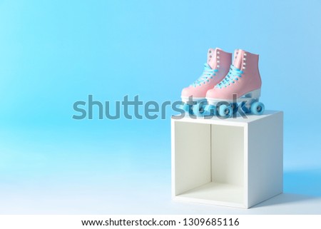 Pair of vintage roller skates on storage cube against color background. Space for text
