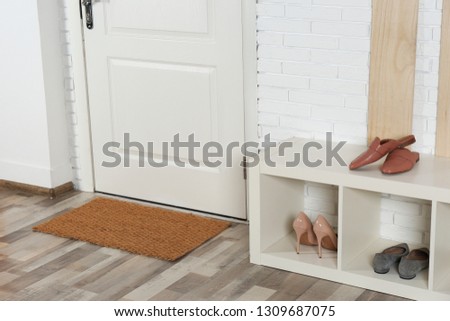 Hallway interior with shoe rack and mat near door Royalty-Free Stock Photo #1309687075