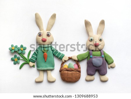 Funny rabbits in clothes with a basket of eggs and flowers. Easter plasticine illustration Royalty-Free Stock Photo #1309688953