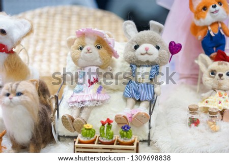 Cute doll. Bunny and kitty dolls sitting together holding hands. Soft focus on the bunny doll holding a pink heart balloon. Love and Valentine's day concept. Toy photography.