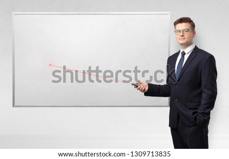 Young businessman with laser pointer and copyspace white blackboard