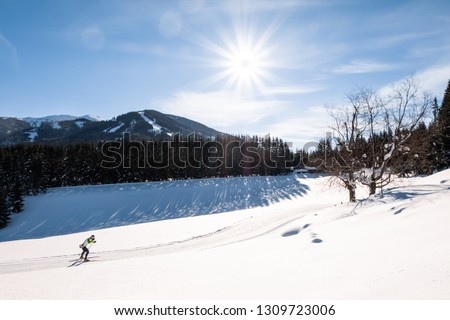Adult man running cross-country skiing in snow-covered holiday resort Hohentauern with the mountain Kleiner Schober in the background