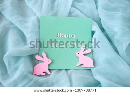 Card with an inscription Happy Easter and a pink rabbits	on a turquoise background