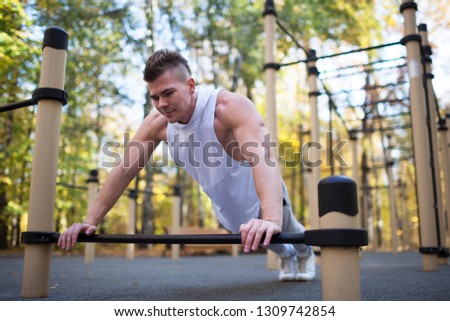 fitness, sport, training and lifestyle concept - young adult fit man doing push-ups outdoors