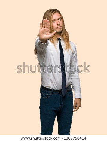 Blond businessman with long hair making stop gesture denying a situation that thinks wrong on isolated background