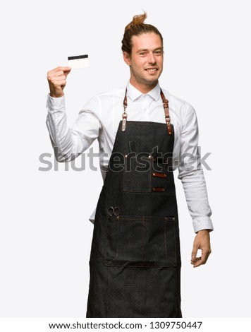 Barber man in an apron holding a credit card on isolated background