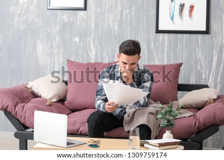 Worried young man in debt at home