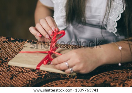 Cropped shot of woman tying ribbon on envelope