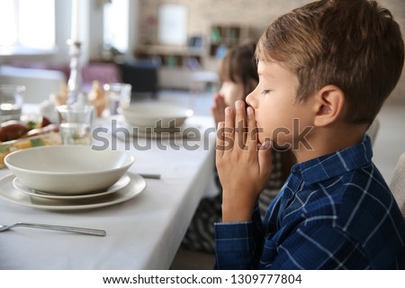 Little boy praying before meal at home