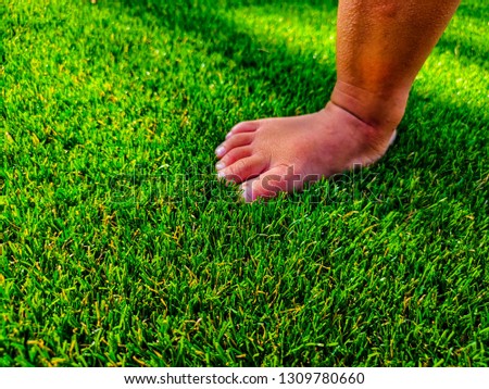 Artificial turf background. Tender baby foots on a green artificial grass floor