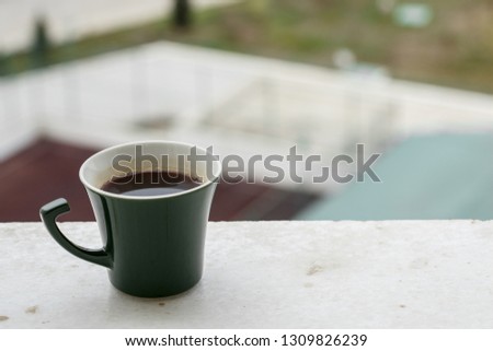Morning coffee in a dark green stylish Cup on a wooden textured background . Photographed in the rays of winter sunlight