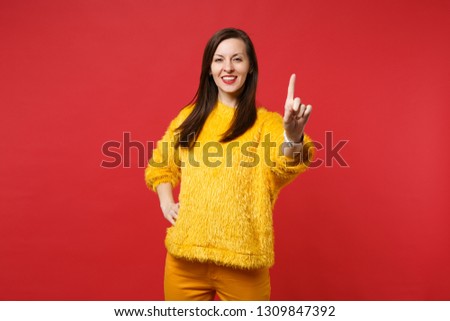 Beautiful young woman touch something like push click on button, pointing at floating virtual screen isolated on red wall background. People sincere emotions, lifestyle concept. Mock up copy space