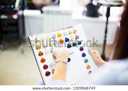 Close up of a female client examining hair color chart at the hairdressing studio coloring dyeing variety changing women hair care. Feminine beauty concept.
