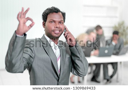 foreground a confident businesswoman showing OK gesture,