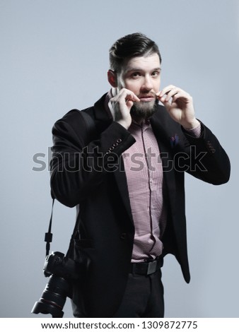fashion photographer with a camera adjusting his moustache