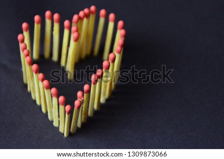 Matches with red head are stuck in a dark area and give the picture of a heart - concept for love and warmth represented with matches