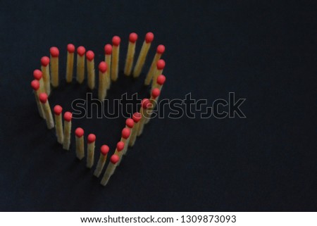 Matches with red head are stuck in a dark area and give the picture of a heart - concept for love and warmth represented with matches