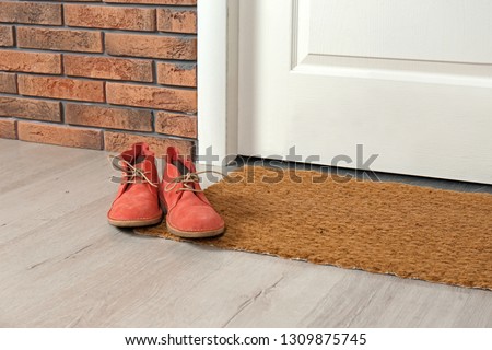 New clean mat with shoes near entrance door