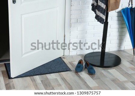 Hallway interior with mat and clothes stand near door Royalty-Free Stock Photo #1309875757