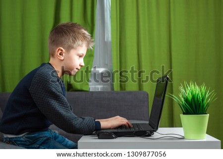 A boy at a laptop plays games, or watches a video. The concept of addiction to computer games, blurred vision, district mental health. copy space