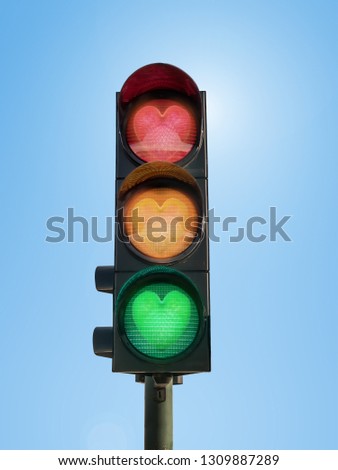 Traffic lights with glowing green, orange and red hearts against blue sky- love concept