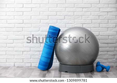 Set of fitness equipment on floor near brick wall. Space for text