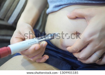 Woman use pre-filled pen syringe for take the FSH (Follicle Stimulating Hormone) to stimulate the ovaries to produce more eggs , initial process for fertility treatment , IVF and ICSI Royalty-Free Stock Photo #1309901185