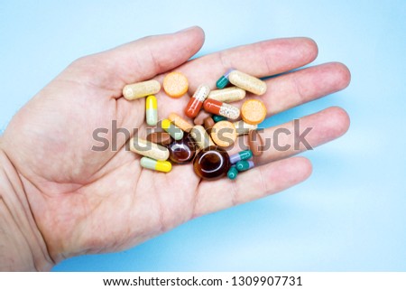 Tablets and pills on the palm of a person. An elderly man holds a lot of colored pills in old hands. Painful old age. Health care of older people. Top View Royalty-Free Stock Photo #1309907731