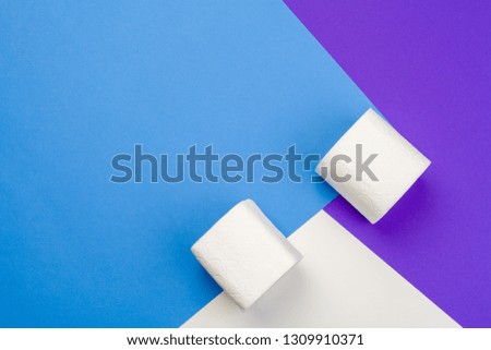 Rolls of unfolded toilet paper on a blue background. Flat lay, top view