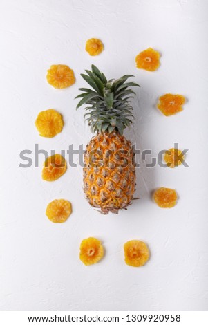 Dried pineapple rings and whole fresh pineapple on white background. Top view, flat lay.