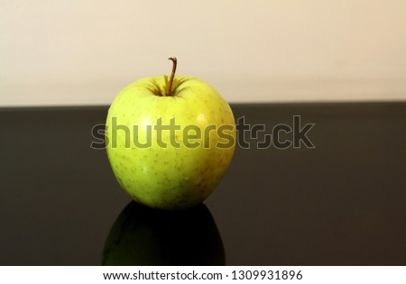 Green apple lies on a black mirror background with reflection