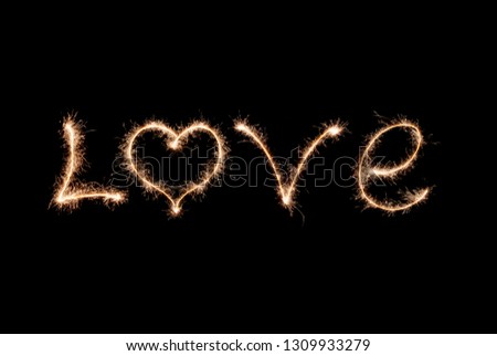 Love word written by sparklers on a black background.