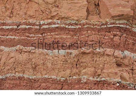 Geological outcrop with layers of earth rock. The texture of the word of soil and clay, which has developed over thousands of years. Archaeological excavations Royalty-Free Stock Photo #1309933867