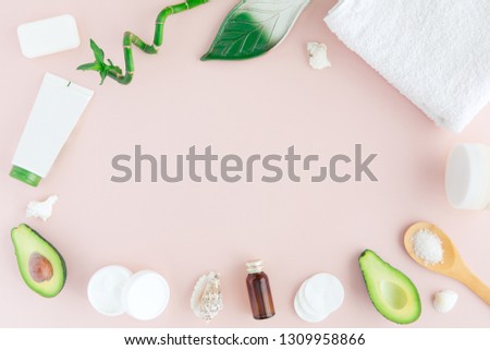 Layout of green white pink spa and wellness frame with towel, bamboo, tropical leaves , avocado, bottle of oil, body and face care tools on pastel background. Flat lay, top view.