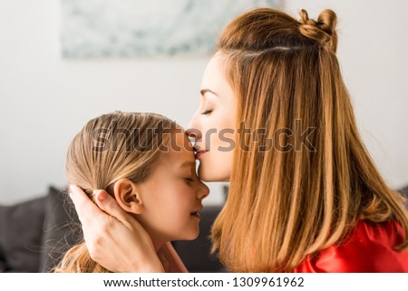 Close up of mother kissing daughter at home 