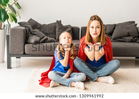 kid and mother in red cloaks blowing air kisses