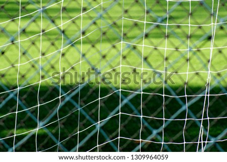 Close up and selective focus picture of white color net of football goal with green field background