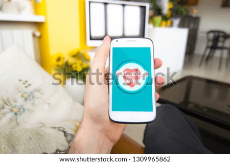Hand holding smartphone in living room with Valentine's day concept on the screen.