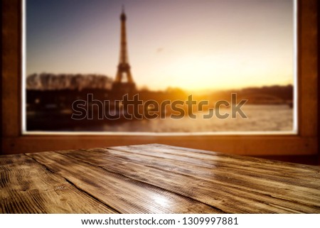 Wooden desk of free space and window sill. City landscape of Paris and sunset time. 