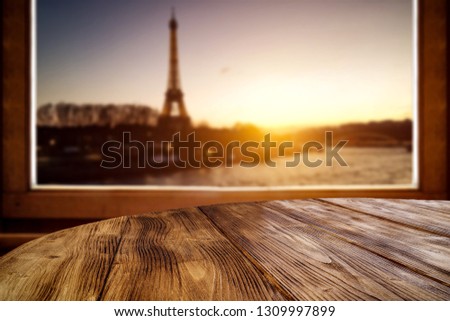 Wooden desk of free space and window sill. City landscape of Paris and sunset time. 