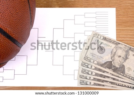 A basketball, tournament bracket and twenty dollar bills